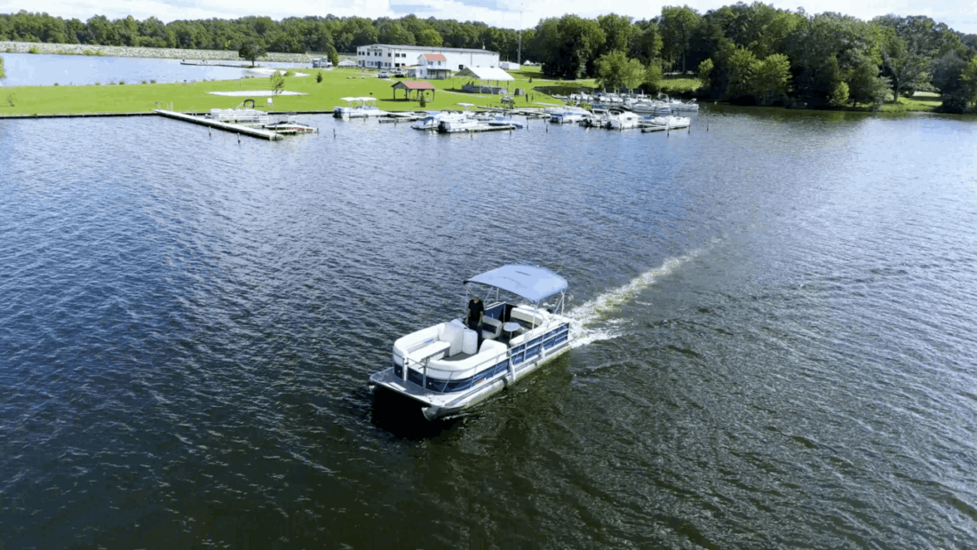 A boat is traveling down the lake near some docks.