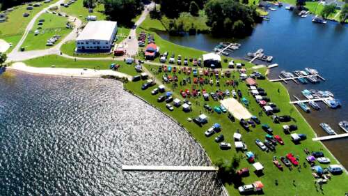 An aerial view of a lake with many cars parked on it.