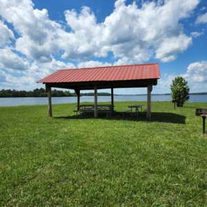 A picnic shelter on the grass near water.