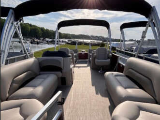 Tan pontoon boat with seats and canopy.