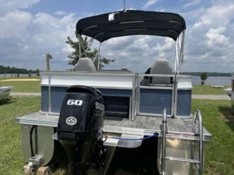 Gray and white pontoon boat with a motor.