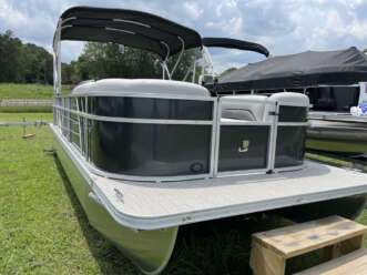 Silver and black pontoon boat on grass.