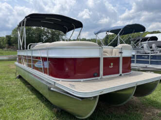 Red and white pontoon boat on grass.