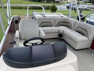 Pontoon boat interior with seating and steering wheel.