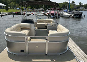 Tan pontoon boat docked at a marina.