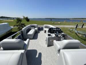 Pontoon boat with white seats and steering wheel.