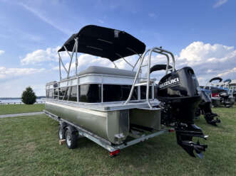 Silver pontoon boat with Suzuki motor.