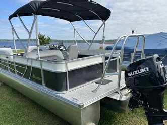 A white and gray pontoon boat with a Suzuki motor.