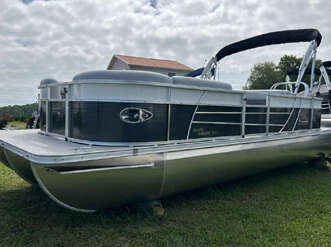 Silver and black pontoon boat on grass.