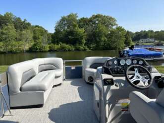 Pontoon boat with a white couch and steering wheel.